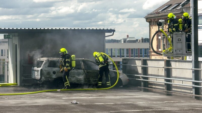 Feuerwehrleute löschen ein brennendes Auto. – Bild: Warner Bros. Discovery, Inc. or its subsidiaries and affiliates.