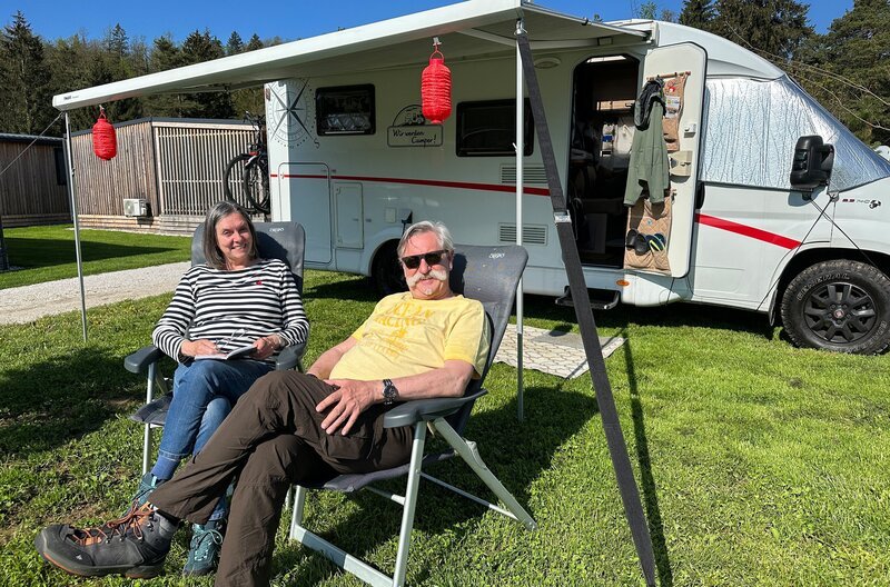 Petra (l.) und Rüdiger (r.) Erbslöh vor ihrem Wohnmobil auf dem Campingplatz River Camping Bled direkt am Bleder See. – Bild: WDR/​Sagamedia