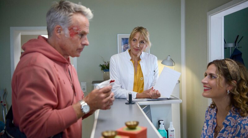 Dr. David Mandel (Marco Girnth, li.) hat sich verlertzt und kommt in die Praxis zu Nora Kaminski (Tanja Wedhorn, Mitte) und Mandy Petersen (Morgane Ferru). – Bild: ARD Degeto Film/​Arnim Thomaß