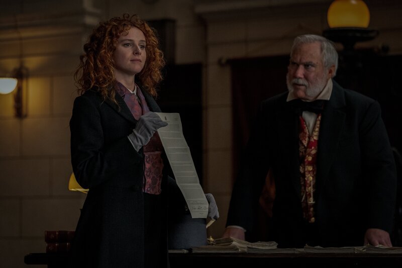 Humility (Georgia Flood, l.) präsentiert dem überraschten Crawley (Damien Garvey, r.) den Vertrag, der sie zur Großaktionärin der Company macht. – Bild: Vince Valitutti/​Disney+