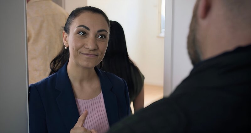 Maklerin Fr. Öztunali (Alev Irmak) unterhält sich mit Pfarrer Reiser (Stephan Zinner). – Bild: maze pictures GmbH /​ BR /​ ORF