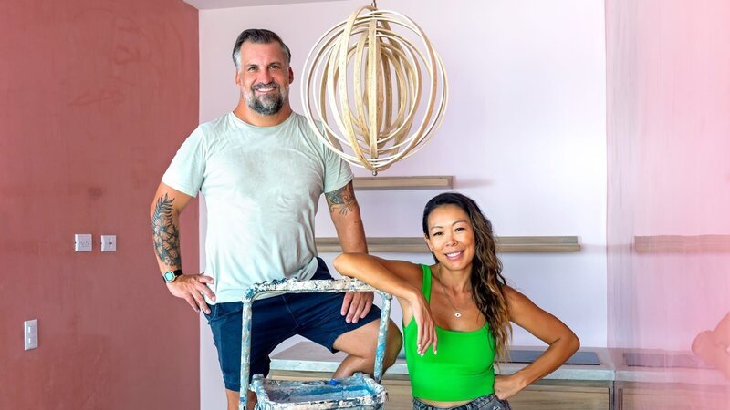 Luke Shantz and Stephanie Sitt portrait with the lamp of the Honeymoon Suite’s kitchen at their renovated hotel in Jaco, Costa Rica, as seen on Betting on Paradise, Season 1. – Bild: Warner Bros. Discovery, Inc. or its subsidiaries and affiliates /​ Pablo Elizondo /​ Getty Images