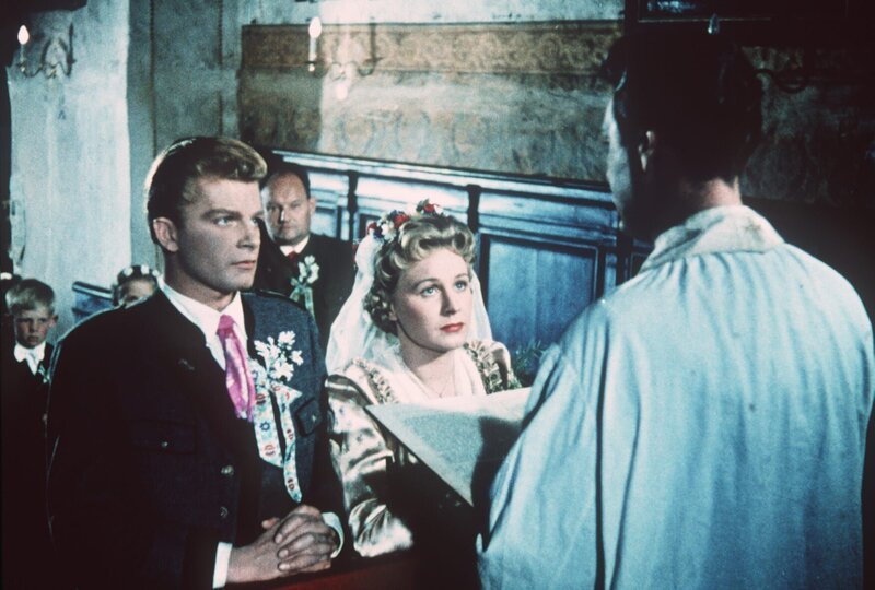 Die Hochzeit zwischen Michel (Albert Rueprecht, l.) und Annerl (Waltraud Haas), vollzogen vom Pfarrer (Erich Auer, von hinten) soll auch den Dorftratsch stoppen, der außer Kontrolle zu geraten droht. – Bild: ZDF und Sepp Ketterer