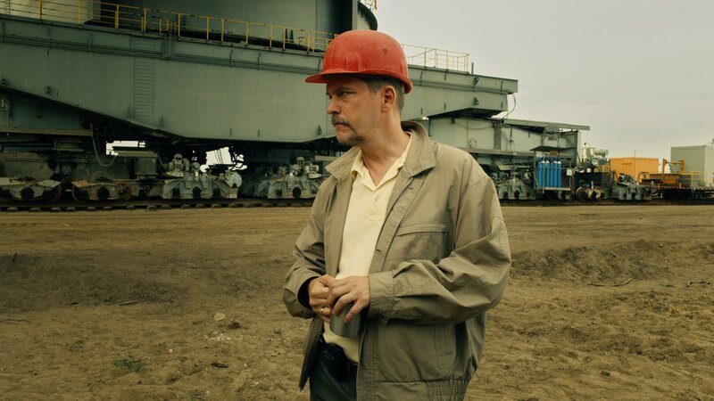 Horàk (Godehard Giese) steht vor dem Abräumbagger. – Bild: ZDF und Sabine Panossian