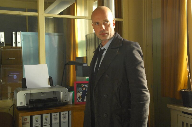 Hauptkommissar Schumann (Christian Berkel) kann der These, dass der Mord an einem Polizisten ein Zufall war, nicht folgen und sucht im Büro des getöteten Kollegen nach Material, das einen Hinweis auf den Hintergrund der Tat geben könnte. – Bild: ZDF und Claudius Pflug