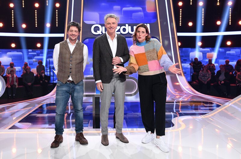 Moderator Jörg Pilawa (M.) mit den Kandidat:innen des Teams „Traumpaar“: Dem Schauspieler Fritz Karl (l.) und der Schauspielerin Elena Uhlig (r.). – Bild: ARD/​Uwe Ernst