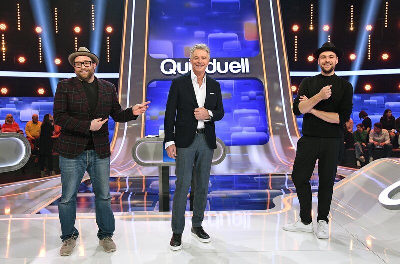 Moderator Jörg Pilawa (M.) mit den Kandidaten des Teams „Songpoeten“: Den Musikern Max Mutzke (l.) und Gregor Meyle (r.). – Bild: ARD/​Uwe Ernst