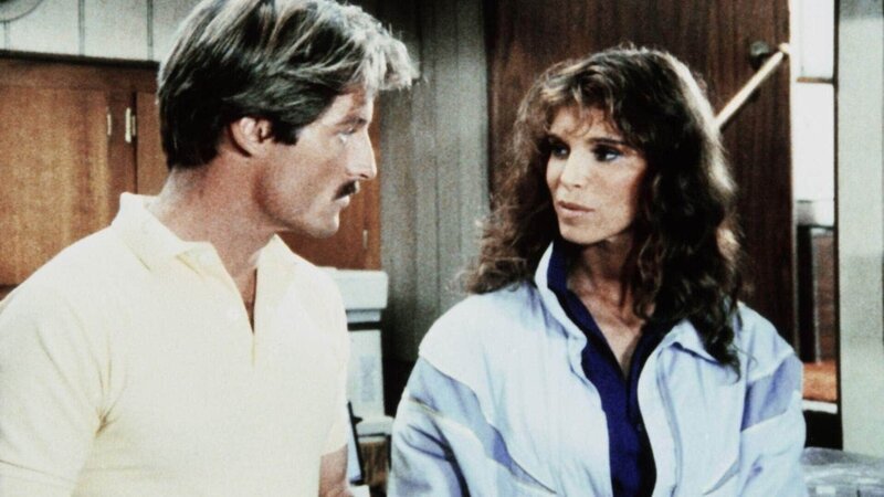 Die attraktive Pilotin Denise (Ann Turkel) erzählt Cody (Perry King), wie sie den exentrischen Erfinder und Millionär Baxter Bernard kennengelernt hat. – Bild: (c) RTL Crime