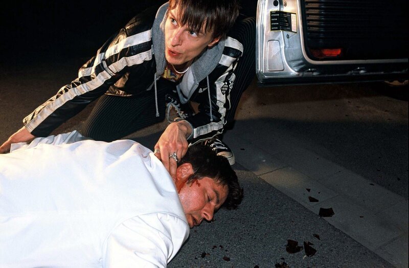 Jupp (Uwe Fellensiek, vorne) überrascht Beck (Alexander Scheer, hinten) bei dem Versuch, das Auto von Hanuman zu klauen, und wird daraufhin von Sandy mit einer Flasche k.o. geschlagen. – Bild: SAT.1 /​ Munstermann