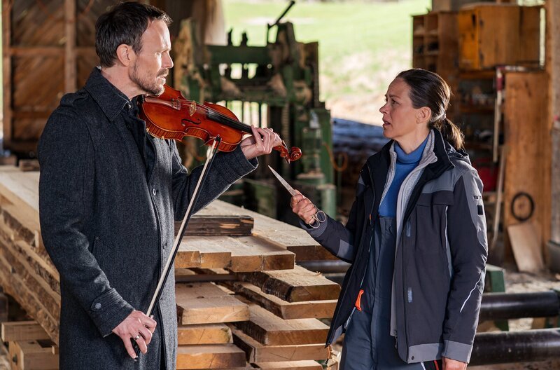 Constantin (Robert Besta) versucht, Sophie (Janina Flieger) mit seinem Geigenspiel zu erweichen. Die fühlt sich aber von ihrem Mann bedroht und richtet eine Waffe gegen ihn. – Bild: SWR/​Christian Koch