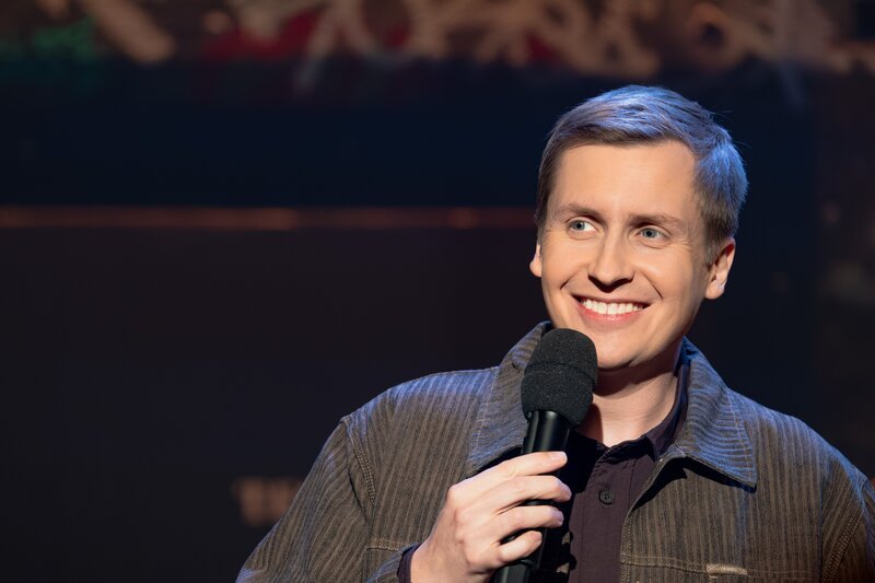 Stand-Up-Comedian und Gastgeber Till Reiners steht mit einem Mikrofon in der Hand auf der Bühne und spricht zum Publikum. – Bild: ZDF/​Hannes Thun