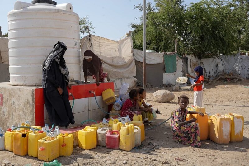 Frauen und Kinder an einer Wasserstelle in einem Vertriebenencamp im Jemen. Wasserknappheit gehört zu den größten Herausforderungen der humanitären Krise. – Bild: Martin Koddenberg