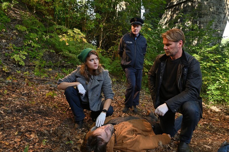 Kommissarin Szabo (Lara Mandoki), Kommissar Winkler (Kai Scheve, r.) und Polizist Steinmetz (Torsten Ranft, 2.v.r.) untersuchen die Leiche von dem Sägewerksbesitzer Matthias Langer (Wanja Mues), der auf dem Jakobsweg zwischen Chemnitz und Stollberg erhängt aufgefunden wurde. – Bild: ORF/​ZDF/​Hardy Spitz