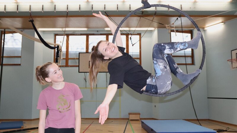 Zirkusschülerin Lisa (links) zeigt der Checkerin eine besondere Zirkusnummer in einem hängenden Ring. – Bild: BR/​megaherz GmbH/​Rebecca Zehr