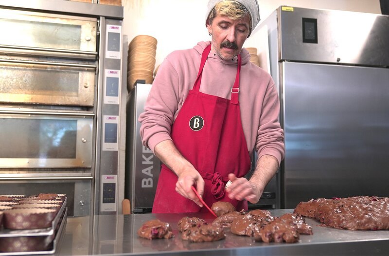 Bäcker Marco Spehar wirkt mit einer Teigspachtel den Teig zu Kugeln und bereitet sie zum Backen vor. – Bild: SWR/​teamWERK/​Dirk Schwarz