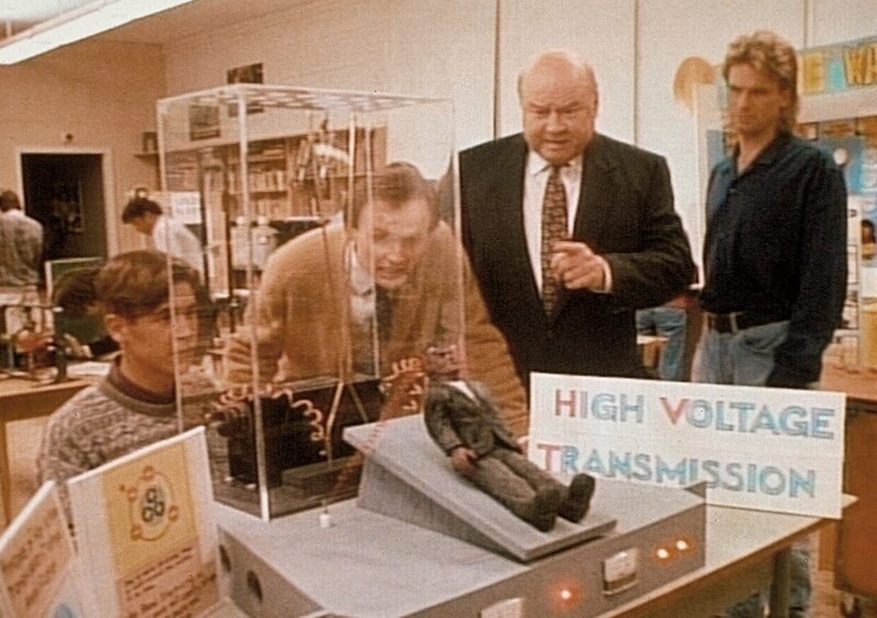 (v.l.n.r.) Der Schüler Mike (Stephen Cooper) führt dem Lehrer Zirkonis (Robert Thurston), Thornton (Dana Elcar) und MacGyver (Richard Dean Anderson) ein Hochspannungsexperiment vor. – Bild: Kabel Eins Classics