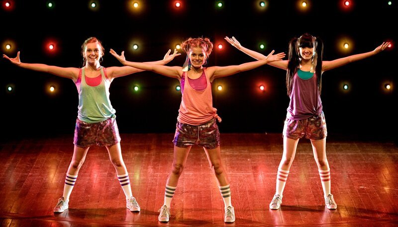 Emma, Ally und Jackie strahlen: sie dürfen am begehrten Tanzworkshop teilnehmen. v.l.: Ally (Marny Kennedy), Emma (Sophie Karbjinski), Jackie (Charlotte Nicdao) – Bild: NDR/​Southern Star