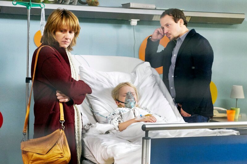 Meike Bender (Jennipher Antoni, li.) wollte ihrem Mann Ingo (Max Hoppe, re.) den Klinikaufenthalt ihres gemeinsamen Sohnes Luis (Georg Arms, mi.) verschweigen. Sie haben sich getrennt, weil Meikes Überfürsorge für Luis zum Mittelpunkt ihrer Beziehung wurde. Nun nähern sie sich langsam wieder an, bei einem Treffen bekommt Meike einen Anruf aus der Sachsenklinik. Nun weiß Ingo, dass Luis schon wieder zu einer Untersuchung beim Arzt ist. Auch die Ärzte sind ratlos, Dr. Brentano vermutet sogar bei der Mutter ein Münchhausen-Stellvertreter-Syndrom. Doch dann geht es Luis tatsächlich schlechter. – Bild: MDR/​Saxonia Media Filmproduktion/​Wernicke