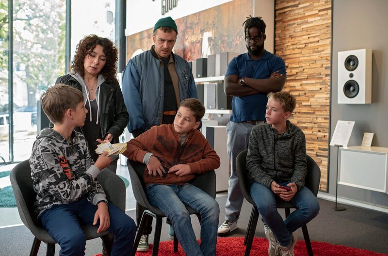 Harry Möller (Maria Ketikidou, 2.v.l.) und Nils Sanchez (Enrique Fiß, hinten M.) versuchen aufzuklären, woher Matthias Nickel (Franz Ferdinand Möller-Titel, l.) so viel Geld hat. Auch dessen Freunde (Henrik Schön, Tim Peters) haben es faustdick hinter den Ohren, wie Ladenbesitzer Carlo (Joel Williams, hinten r..) geahnt hat. – Bild: ARD/​Thorsten Jander