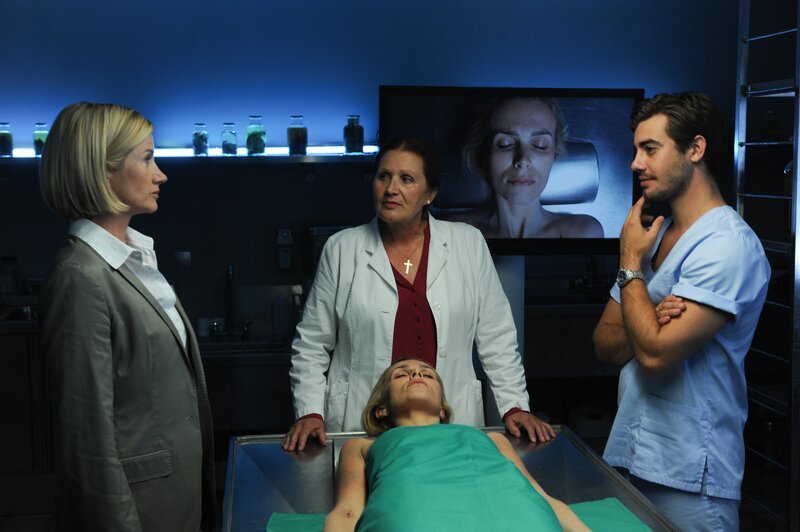 Martina Seiffert (Astrid M. Fünderich, l.) trifft Prof. Lisa Wolter (Eva Maria Bayerwaltes, M.) und Benedikt Förster (Florian Wünsche, r.) in der Rechtsmedizin und bekommt den Befund der Leichenbeschauung erklärt: Anita Reitberger (Komparsin, liegend) wurde mit einer Überdosis eines synthetischen Opioids vergiftet. – Bild: ZDF/​MARKUS-FENCHEL