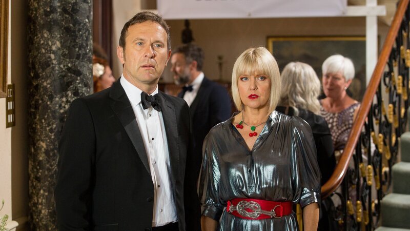 Charles Fraiths (Jason Merells) und Agatha Raisin (Ashley Jensen) sind verwirrt, als sie James mit Melissa zusammen sehen, die sich Agatha anschließend als James’ Schreibpartnerin vorstellt. – Bild: ZDF