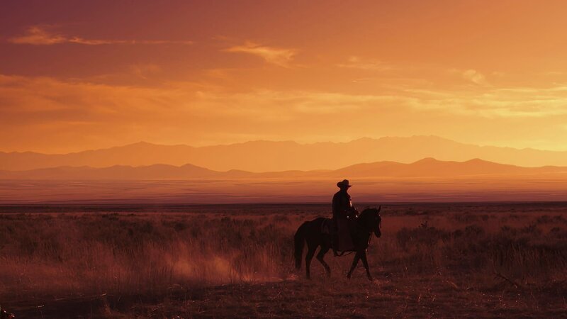 Ein Tejano-Cowboy reitet bei Sonnenuntergang durch die texanische Landschaft. – Bild: Courtesy of Disney+