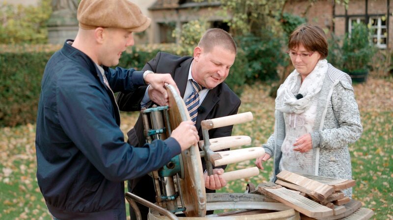 André (m) und Astrid haben Oli P. (l) die Einzelteile einer alten Holz-Waschmaschine mitgebracht. – Bild: WDR/​Encanto Film- und Fernsehproduktions GmbH