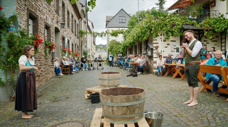 In Mesenich fordert Sören Anders (re.) die Weltrekordhalterin im Traubenstampfen, Martina Servaty (li.), heraus. – Bild: SWR/​Norbert Lübbers
