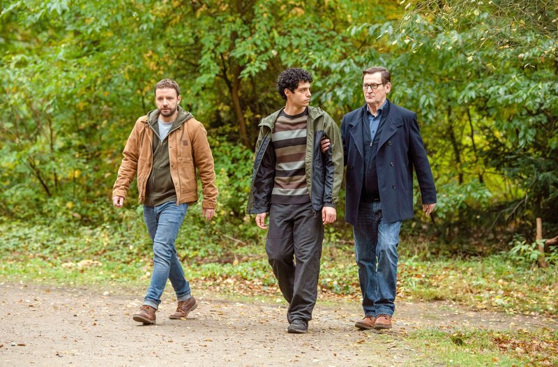 Nach seinem Fluchtversuch führen Gregor (Jonas Minthe, l.) und Lars (Ingo Naujoks, r.) Tarik Bashar (Baris Gul, M.) ab. Hat er etwas mit dem Mord an Daniel Kramer zu tun? – Bild: ORF/​ONE GATE/​ARD/​Thorsten Jander