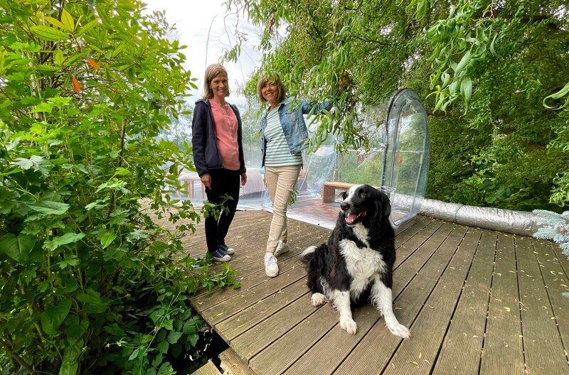 Gastgeberin Caroline Barth vom Feierlenhof im Thurgau (Schweiz) zeigt Moderatorin Annette Krause, wie die transparente Kugel funktioniert: Mit ständiger Luftzufuhr. – Bild: SWR/​Kerstin Raddatz /​ SWR Presse/​Bildkommunikation
