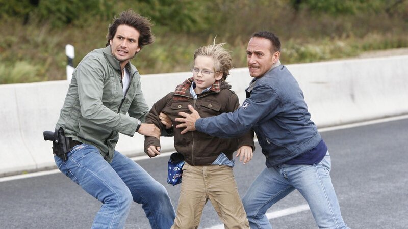 Ben (Tom Beck, li.) und Semir (Erdogan Atalay, re.) können in letzter Sekunde den kleinen Felix (Mateo Wansing Lorrio) retten, bevor er von den heranrasenden Autos überfahren wird … – Bild: RTL