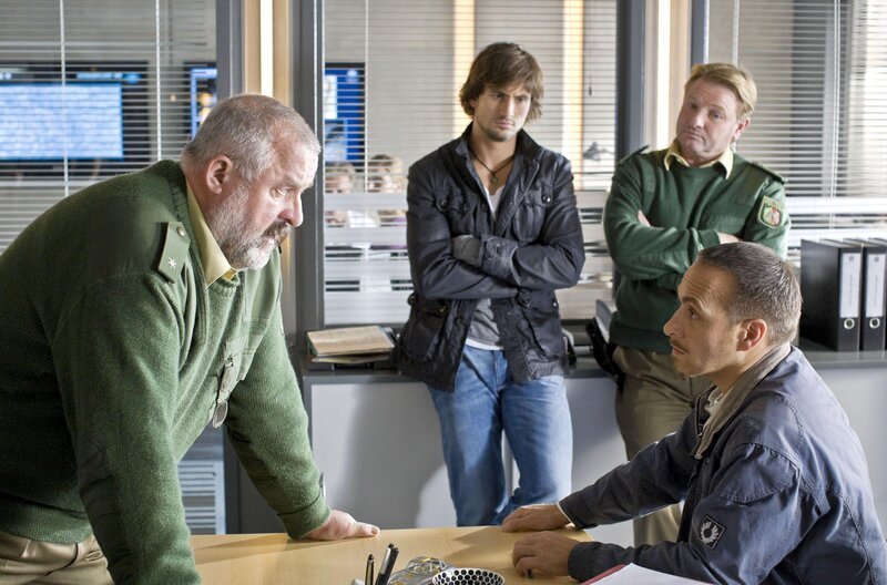 Ben (Tom Beck, 2.v.li.), Semir (Erdogan Atalay, re.) und ein Kollege (Siggi Müller, hi.re.) sprechen gerade über Susanne, als Herzberger (Dietmar Huhn) die neue Chefin Kim Krüger ankündigt. – Bild: RTL /​ Guido Engels