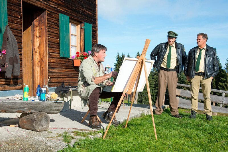 Hubert (Christian Tramitz, rechts) und Staller (Helmfried von Lüttichau, Mitte) sprechen mit dem Porträtmaler Herbert Stein (Johann Schuler). Der grantige Bayer war der beste Freund des Opfers und hatte noch am Tattag Besuch von Dr. Quirin Meyer auf seiner Hütte. – Bild: ARD/​TMG/​Marco Meenen