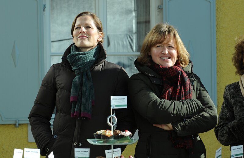 Vroni verschenkt kleine Muffins an die Lansinger Wählergemeinschaft. Von links: Annalena (Heidrun Gärtner) und Veronika Brunner (Senta Auth). – Bild: BR/​Marco Orlando Pichler