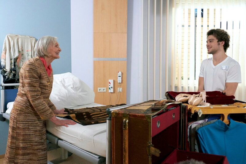 Renate Harnack (Katharina Matz), eine ehemalige Tänzerin, kommt zur Entfernung ihrer Nierensteine in die Sachsenklinik. Sie hat einen riesigen Übersee-Koffer dabei, in dem sich neben einer ausführlichen Garderobe und einigen Haus- und Dekorationsgegenständen auch eine Heizdecke findet. Kris Haas (Jascha Rust) muss der eloquenten Dame allerdings den Gebrauch derselben untersagen. Heizdecken sind in der Sachsenklinik nicht erlaubt. Doch lange kann Kris dem Charme von Frau Harnack nicht widerstehen und erlaubt ihr die kleine Normübertretung. – Bild: MDR/​Saxonia/​Wernicke