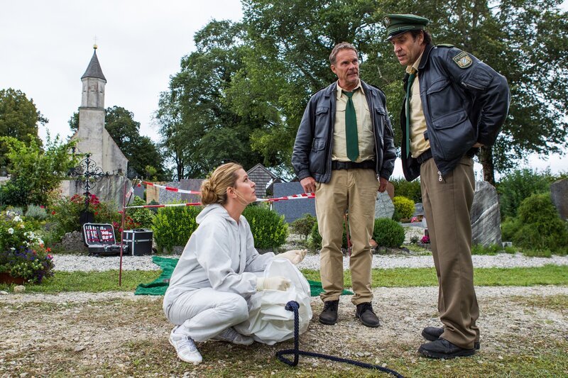 Hubert (Christian Tramitz, M.) und Staller (Helmfried von Lüttichau, r.) suchen gemeinsam mit Dr. Anja Licht (Karin Thaler, l.) nach Hinweisen auf ein Motiv, für den Mord an dem beliebten Totengräber der Gemeinde. – Bild: Christian Hirschhäuser