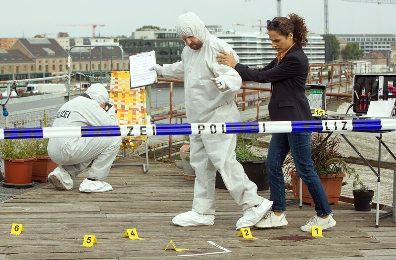 Auf der Start Up-Terrasse über der Spree, stellt Jasmin Sayed (Sesede Terziyan, r.) den möglichen Tathergang nach (mit Komparsen). – Bild: ARD/​Daniela Incoronato
