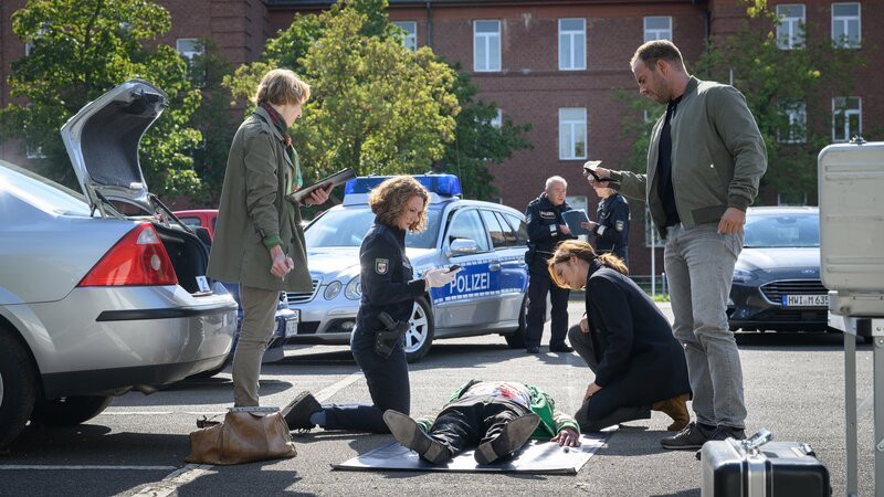 Paula Moorkamp (Stella Hinrichs, 2.v.l.) wird zur KfZ-Verwahrstelle gerufen, da eine Beamtin Blut an einem Auto entdeckt hat. Tatsächlich befindet sich im Kofferraum die Leiche von Matteo Ritter (Omar Yussuf Bousnali, M.). Laut Dr. Helene Sturbeck (Katharina Blaschke, l.) wurde er überfahren. Ob das die Todesursache war, kann sie Karoline Joost (Nike Fuhrmann, 2.v.r.) und Lars Pöhlmann (Dominic Boeer, r.) allerdings erst nach einer genaueren Untersuchung sagen. – Bild: ZDF /​ Meyerbroeker