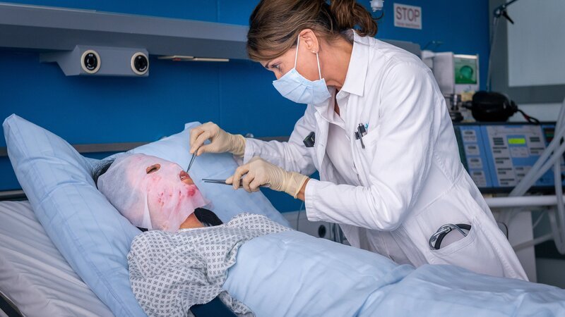 Jasmin (Gerit Kling, r.) wundert sich über das Ausmaß von Mychau Les (Trang Le Hong, l.) Verletzungen, die von einer Verbrühung kommen sollen. – Bild: Boris Laewen /​ ZDF