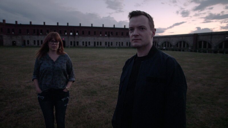 Paranormal Investigators Amy Bruni and Adam Berry, at Fort Adams, Newport RI, Discuss Case with fort in background – Bild: Travel Channel