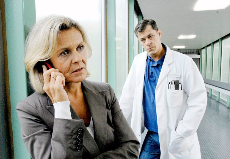 Christine Herzog vom Jugendamt (Andreas L’Arronge, l.) und Dr. Christoph Lentz (Sven Martinek, r.) warten schon geraume Zeit ungeduldig auf Luisas Eltern. Frau Herzog wird von ihrem Amtsleiter darüber informiert, dass die Eltern ihre Therapie abgebrochen haben und nicht auffindbar sind. – Bild: Christa Köfer