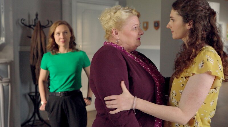 Rosi Heinzmann (Angelika Sedlmeier, M.) und ihre Tochter Lena Heinzmann (Anuschka Tochtermann, r.) halten sich in den Armen, als Lena ihrer Mutter alles gesteht. Sophia Strasser (Katharina Goebel, l.) beobachtet das liebevolle Geschehen. – Bild: ARD/​Sascha Ersfeld