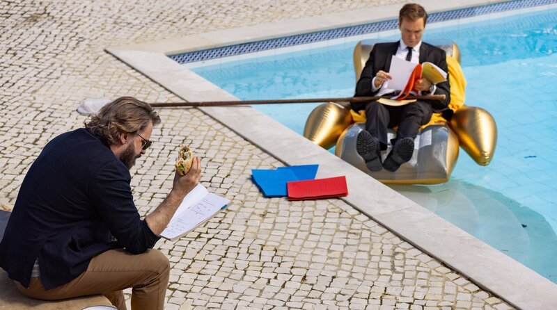 Entspanntes Aktenstudium: Europol-Kommissar Leander Lost (Jan Krauter) und Inspektor Esteves (Daniel Christensen, li.). – Bild: ARD Degeto Film/​307 Production GmbH/​João Guimarães