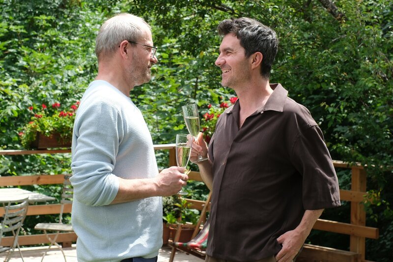 Dr. Stefan Keller (Thomas Limpinsel, l.) und Rob Manzini (Seán McDonagh) feiern die gemeinsame Wohnungssuche von Dr. Keller und Julia Obermeier. – Bild: Jacqueline Krause-Burberg /​ ZDF