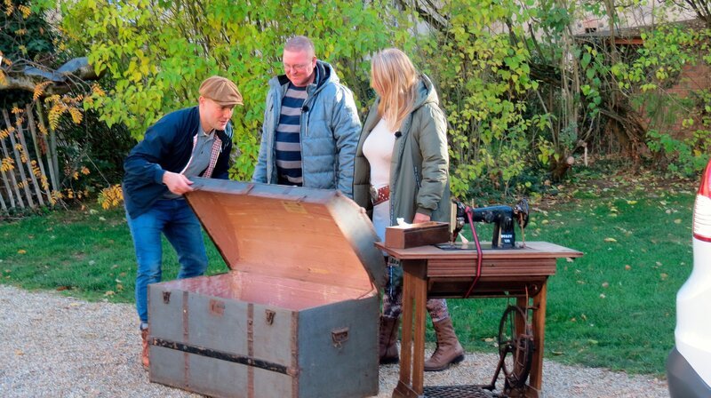 Oli P. (l) inspiziert die große Truhe, die Haucke und Angela ihm mitgebracht haben. – Bild: WDR/​Encanto Film- und Fernsehproduktions GmbH