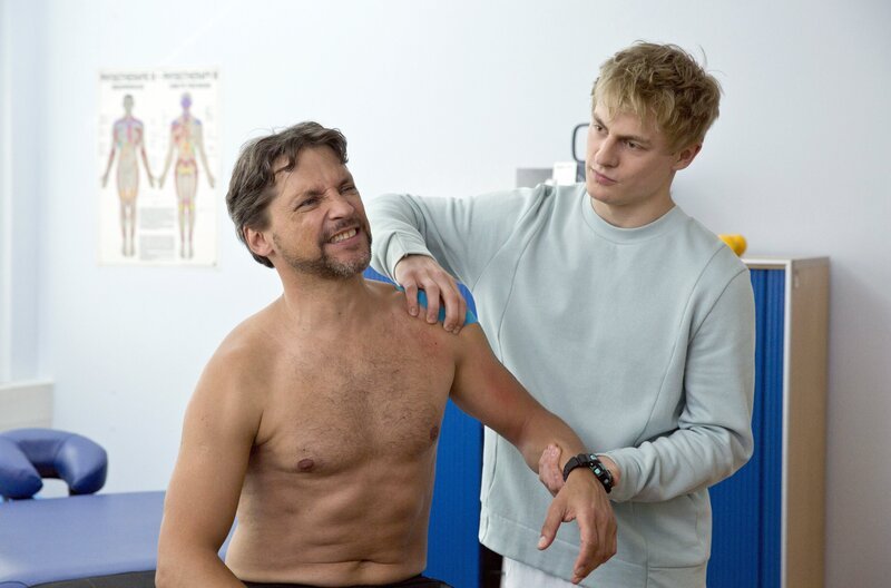 Piwis (Meo Wulf, r.) ehemaliger Fitnesstrainer Robert Feldmann (Patrick Bach, l.) ist wieder in Eisenach und wird Piwis erster Patient. – Bild: ARD/​BR/​Volker Roloff