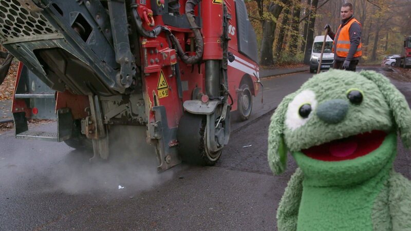 Knolle erfährt, wie der Asphalt auf der Straße erneuert wird. – Bild: WDR/​Die Sendung mit dem Elefanten