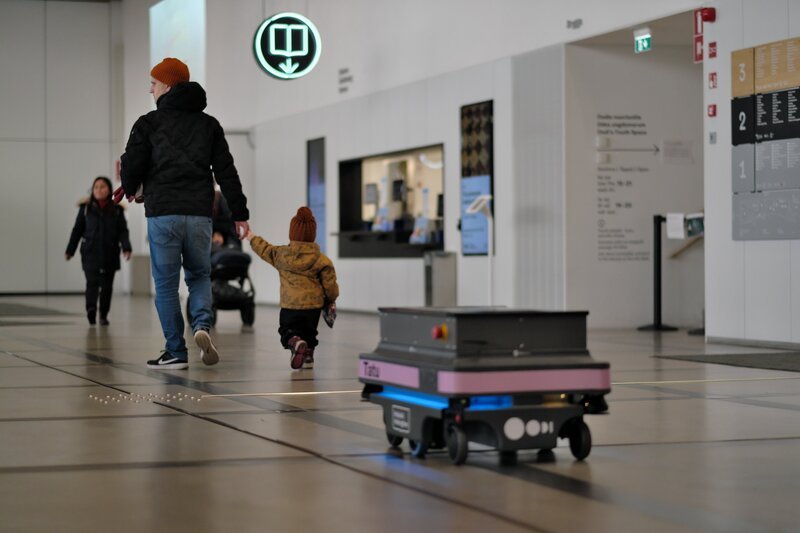 „Tatu“ ist einer von drei Robotern, die im „Oodi“ für alle sichtbar Logistikaufgaben übernehmen. Ganz bewusst hat man sich in Helsinkis neuer Leuchtturm-Bücherei dafür entschieden, Roboter auch im „Vordergrund“ arbeiten zu lassen. Denn die Nutzerinnen und Nutzer sollen hier in direkten Kontakt mit der automatisierten Arbeitswelt des 21. Jahrhunderts kommen. – Bild: Christoffer Maid /​ ZDF