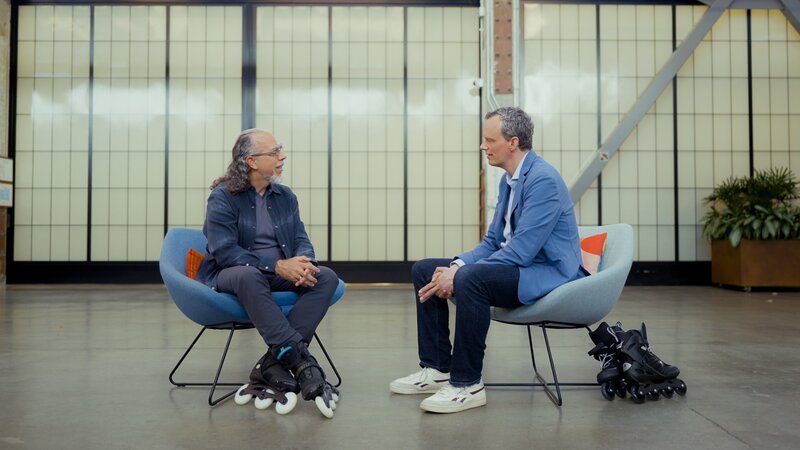 Florian Neuhann (r.) spricht in einer großen Lagerhalle mit Astro Teller (l.), dem CEO der Moonshot Factory. Im Silicon Valley glaubt man fest an eine positive Zukunft durch KI. – Bild: Leonard Bendix /​ ZDF