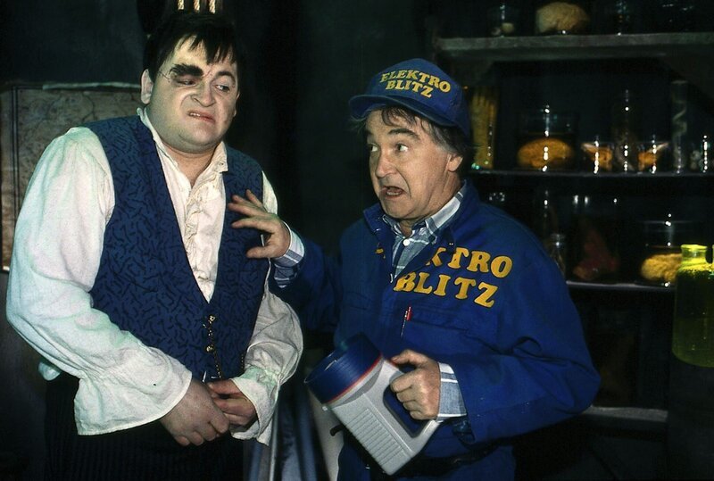 Der Elektriker (Victor Deiß, r.) hat seine Brille verloren und ist daher fast blind. Trotzdem hat Lenni (Michael Trischan, l.) Angst, dass er erkannt wird. – Bild: ZDF/​Jörg Wigger